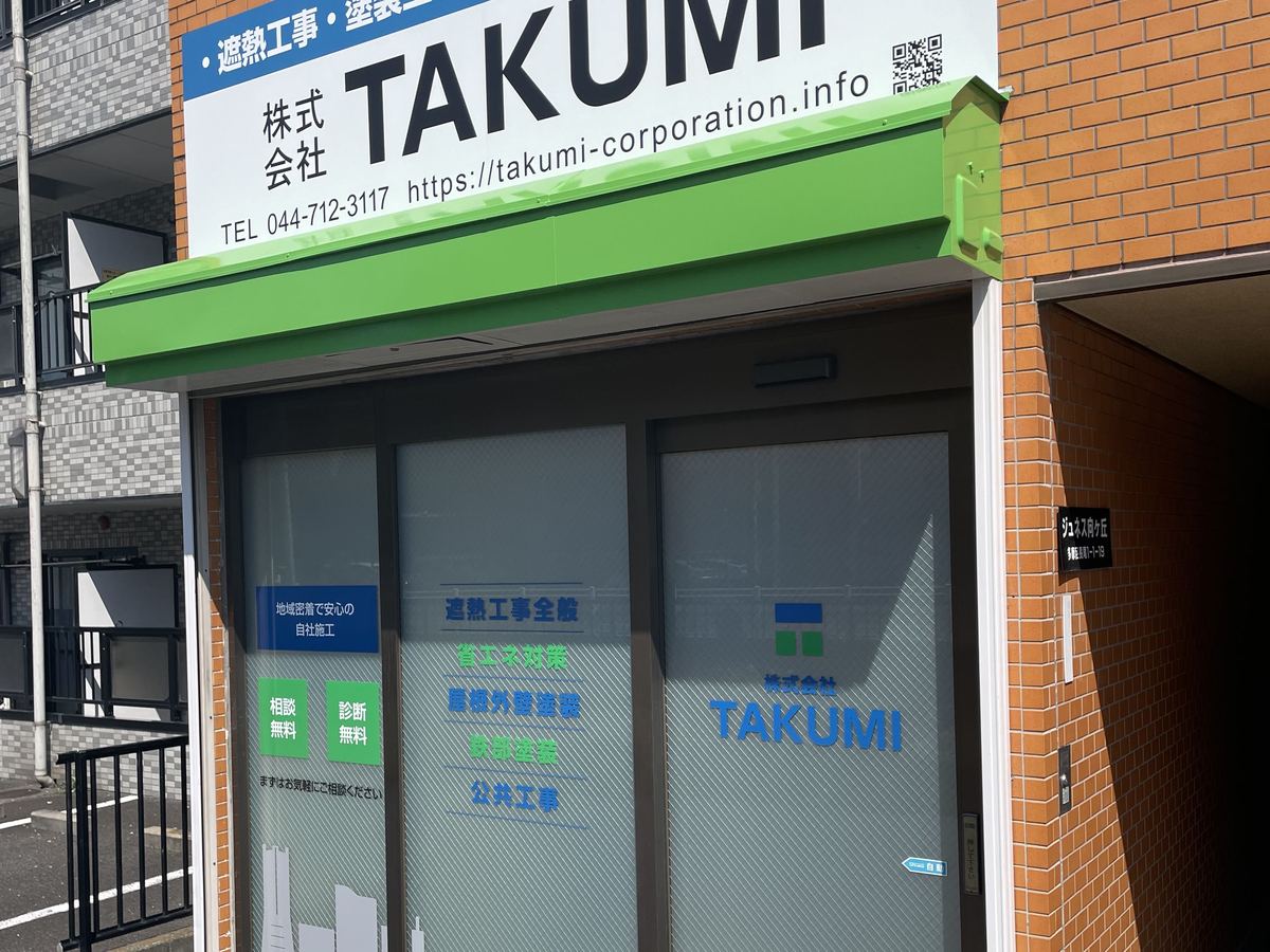 株式会社TAKUMIの本社外観。「株式会社TAKUMI 遮熱工事・塗装工事」の看板と、ガラス戸の入口
